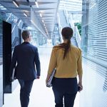 Rear view of businesswoman and man walking through office atrium