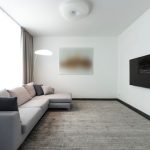 What landlords should check before replacing carpet between tenancies Contemporary living room with a gray sectional sofa and a wall-mounted TV.